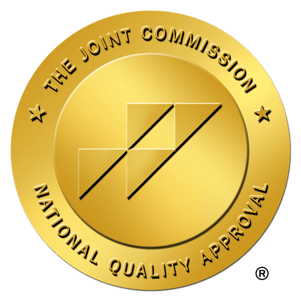 Gold accreditation seal reading 'The Joint Commission National Quality Approval' around the edge, with a central geometric design inside a circle.